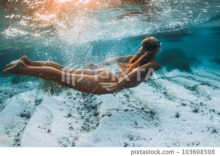 Blonde woman snorkeling underwater in blue ocean. 103608508