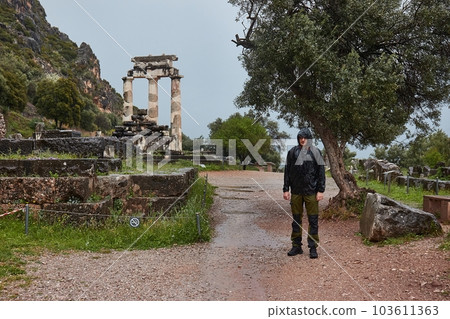 Ancient greek ruins in Delphi, tourist in the rain Ancient greek ruins in Delphi, tourist in the rain 103611363