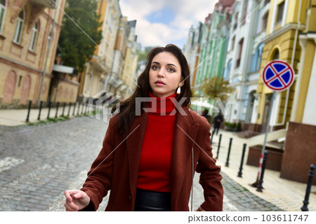 Young woman stares anxiously. A woman walks down the street anxiously looking ahead. 103611747