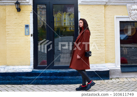 Young stylish woman walks down the street in a brown coat Young stylish woman walks down the street in a brown coat 103611749