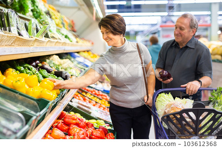 Smiling happy couple is choosing bell peppers and other vegetables in supermarket Smiling happy couple is choosing bell peppers and other vegetables in supermarket 103612368