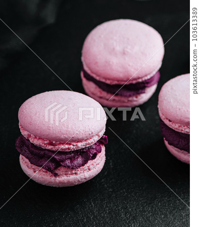 Pink macarons with chocolate filling on black stone 103613389
