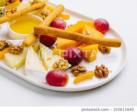 cheese platter with honey, nuts and red grapes 103613840