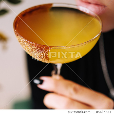 girl drinking yellow banana cocktail in martini glass 103613844