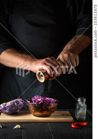 The cook adds pepper to a fresh red cabbage salad. Cooking healthy food in restaurant kitchen on vintage table The cook adds pepper to a fresh red cabbage salad. Cooking healthy food in restaurant kitchen on vintage table 103613978