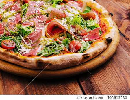 Pizza with prosciutto meat, cherry tomatoes, arugula and parmesan cheese 103613980