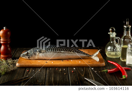 Mackerel or Scomber fish on kitchen cutting board before cooking with spices and pepper. European cuisine. Mackerel or Scomber fish on kitchen cutting board before cooking with spices and pepper. European cuisine. 103614116