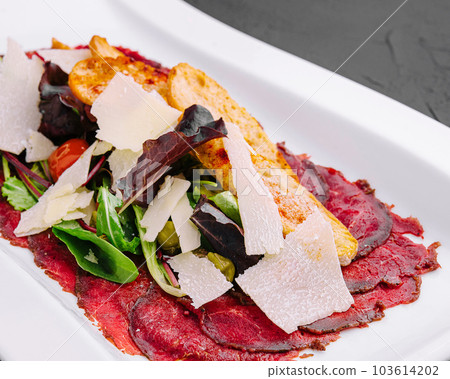 Beef carpaccio with salad and Parmesan on a white plate Beef carpaccio with salad and Parmesan on a white plate 103614202
