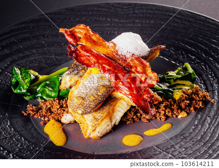 Fried fish with bacon on plate 103614211