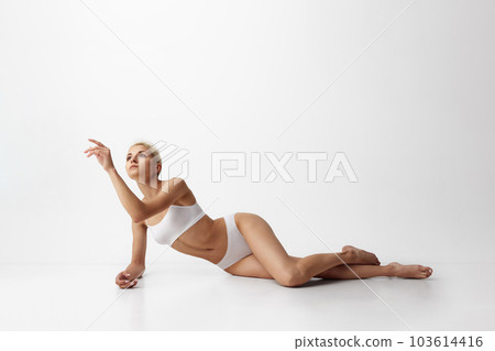 Tenderness. Portrait of young attractive woman with slim, fit body shape posing in underwear against grey studio background Tenderness. Portrait of young attractive woman with slim, fit body shape posing in underwear against grey studio background 103614416