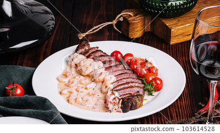 Savory turkey fillet with shrimp sauce, cherry tomatoes, and a glass of red wine. 103614528