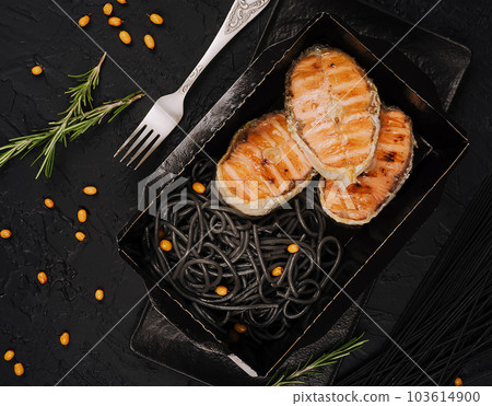 Italian salmon served over black spaghetti noodles 103614900