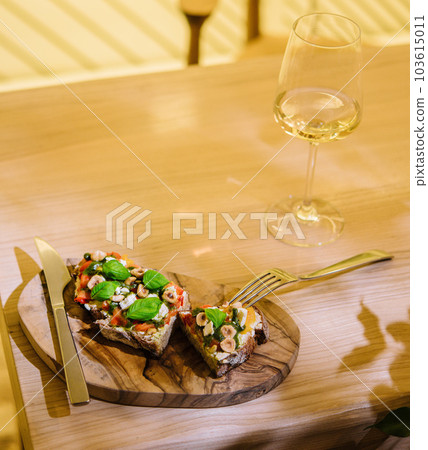 Glass of wine and bruschetta with pesto sauce, feta cheese, tomatoes and basil Glass of wine and bruschetta with pesto sauce, feta cheese, tomatoes and basil 103615011