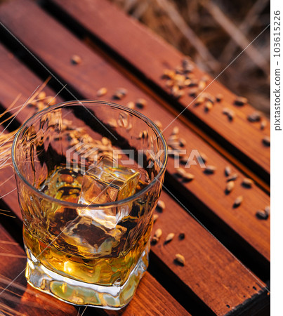 a glass of whiskey in a wheat field 103615226