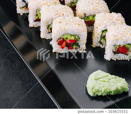 vegetarian sushi maki rolls with sesame seeds on black plate 103615551