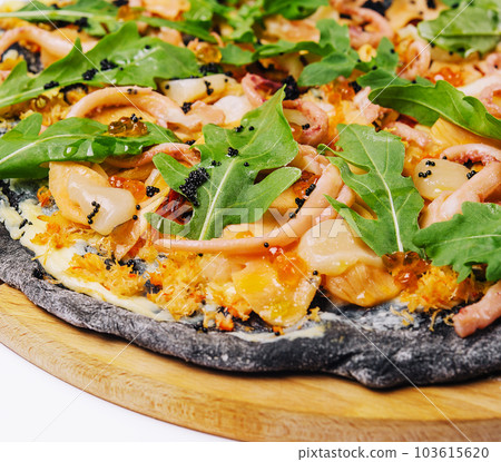 Black pizza with seafood on a wooden round plate on a white Black pizza with seafood on a wooden round plate on a white 103615620