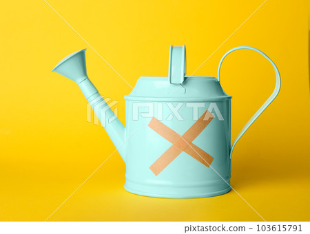 Light blue watering can with sticking plasters on yellow background 103615791