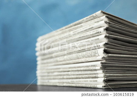 Stack of newspapers on blue background, closeup. Journalist's work 103615819