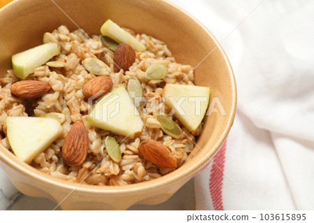 Tasty oatmeal with apples and almonds on table, closeup. Healthy breakfast 103615895