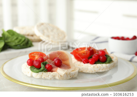 Puffed rice cakes with prosciutto, berries and basil on table, closeup 103616253