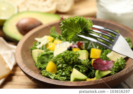 Delicious kale salad in wooden bowl, closeup Delicious kale salad in wooden bowl, closeup 103616297