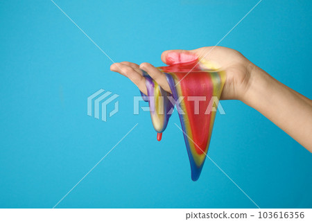 Woman playing with colorful slime on light blue background, closeup. Antistress toy 103616356