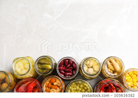 Glass jars with different pickled vegetables on light grey marble table, flat lay. Space for text Glass jars with different pickled vegetables on light grey marble table, flat lay. Space for text 103616382