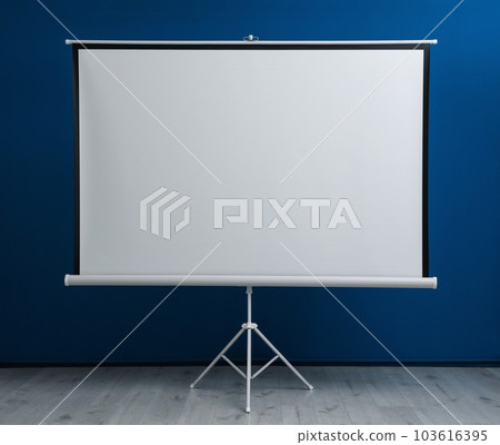 Blank projection screen near blue wall indoors. Space for design 103616395