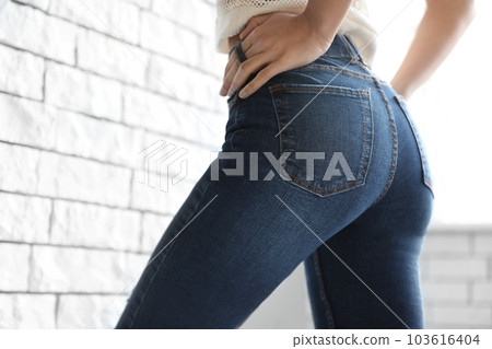Woman wearing jeans near brick wall indoors, closeup 103616404