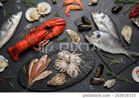 Fresh fish and different seafood on black table, flat lay 103616535