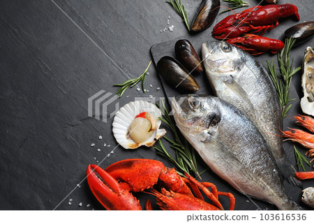 Fresh fish and different seafood on black table, flat lay. Space for text Fresh fish and different seafood on black table, flat lay. Space for text 103616536