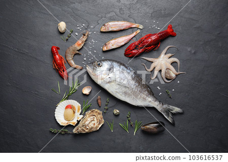 Fresh fish and different seafood on black table, flat lay 103616537