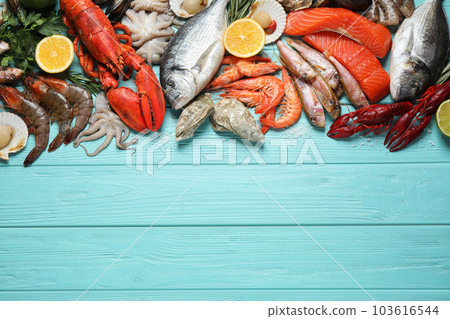 Fresh fish and different seafood on blue wooden table, flat lay. Space for text Fresh fish and different seafood on blue wooden table, flat lay. Space for text 103616544