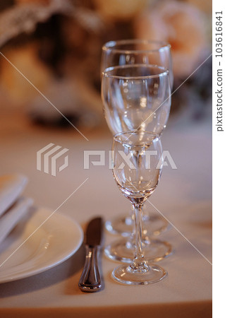 Three crystal or glass goblets on tables served 103616841