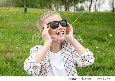Cute boy put on colorblind sunglasses and laughs. Snow-white teeth in a boy in sunglasses 103617560