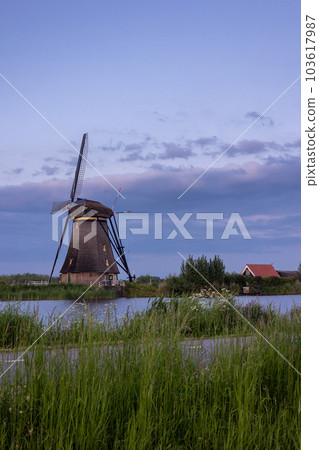 Beautiful wooden windmills at sunset in the Dutch village of Kinderdijk. Windmills run on the wind. The beautiful Dutch canals are filled with water. Beautiful sunset. 103617987