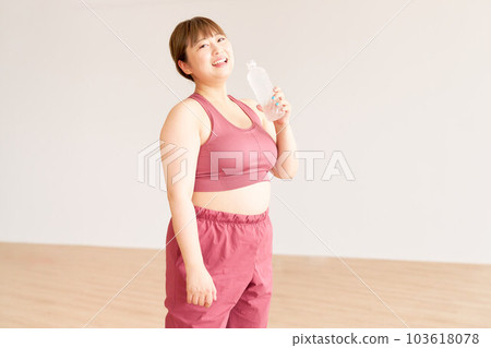 A smiling chubby girl holding a plastic bottle of water, a plus-size model, exercising 103618078