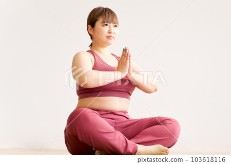 Young woman wearing yoga wear sitting and putting her hands together Young woman wearing yoga wear sitting and putting her hands together 103618116