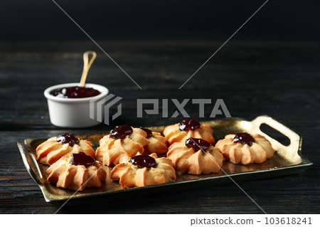 Tasty shortbread cookies with jam on black wooden table 103618241