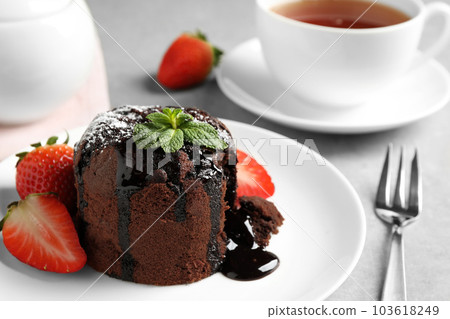 Delicious warm chocolate lava cake with mint and strawberries on table, closeup Delicious warm chocolate lava cake with mint and strawberries on table, closeup 103618249