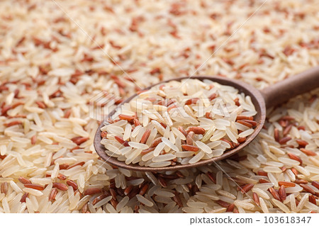 Mix of brown and polished rice with wooden spoon, closeup 103618347