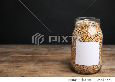 Organic green buckwheat in jar with blank label on wooden table. Space for text 103618360