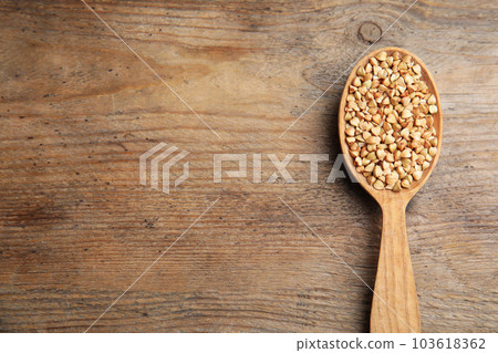 Spoon with green buckwheat on wooden table, top view. Space for text 103618362