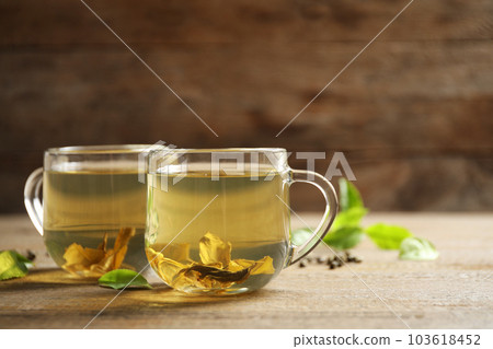 Cups of green tea and leaves on wooden table 103618452