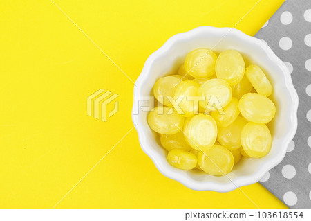 Delicious lemon drops in bowl on yellow background, flat lay. Space for text Delicious lemon drops in bowl on yellow background, flat lay. Space for text 103618554