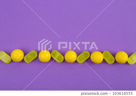 Delicious lemon candies on purple background, flat lay Delicious lemon candies on purple background, flat lay 103618555