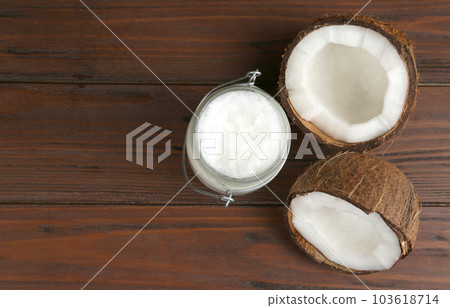 Halves of ripe coconut and organic oil on wooden table, flat lay with space for text. Healthy cooking Halves of ripe coconut and organic oil on wooden table, flat lay with space for text. Healthy cooking 103618714