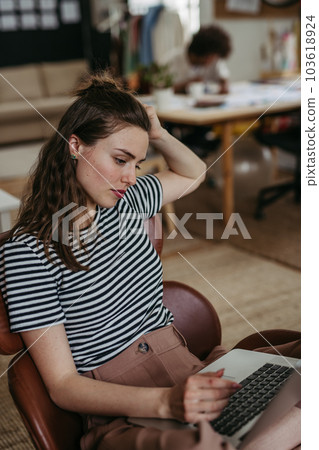 Young woman working on laptop in creative studio. Young woman working on laptop in creative studio. 103618924