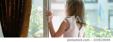 Little girl in pink dress standing on windowsill at open window 103619094