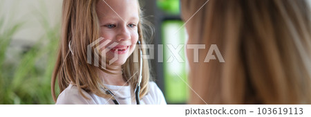 Happy little kid having fun with stethoscope at doctor appointment 103619113